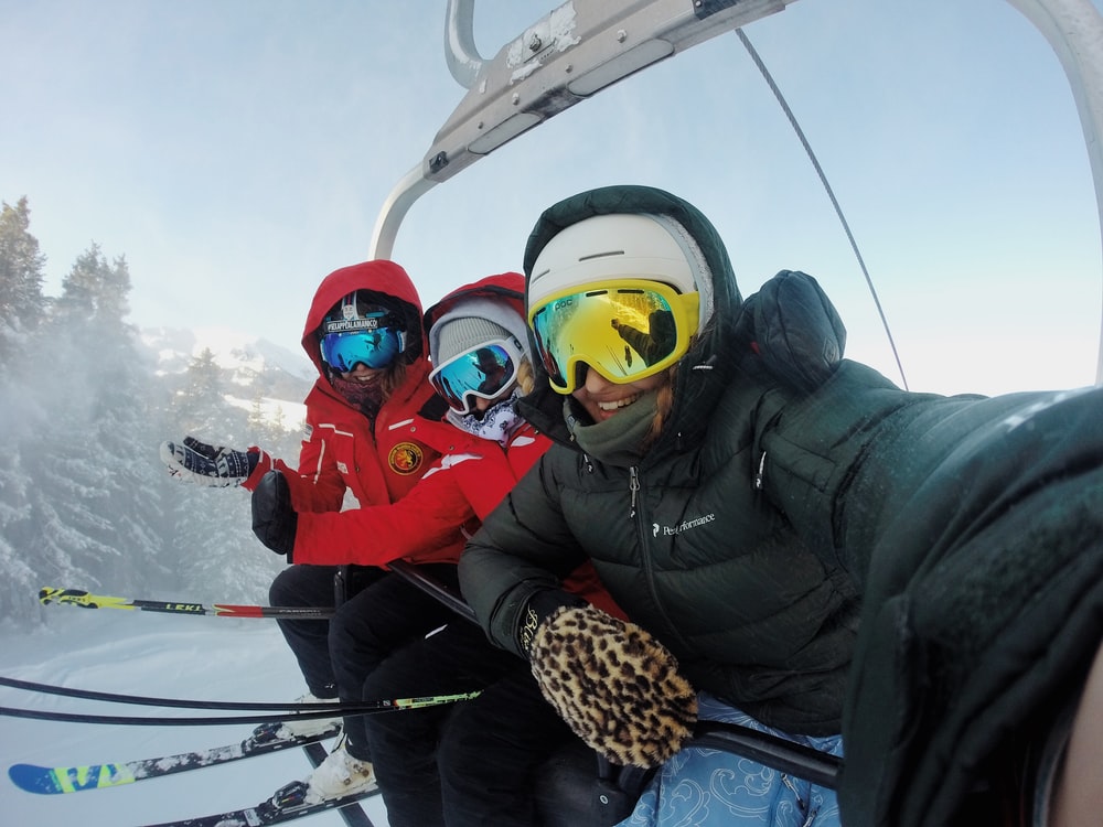three person wearing ski gear riding cable car