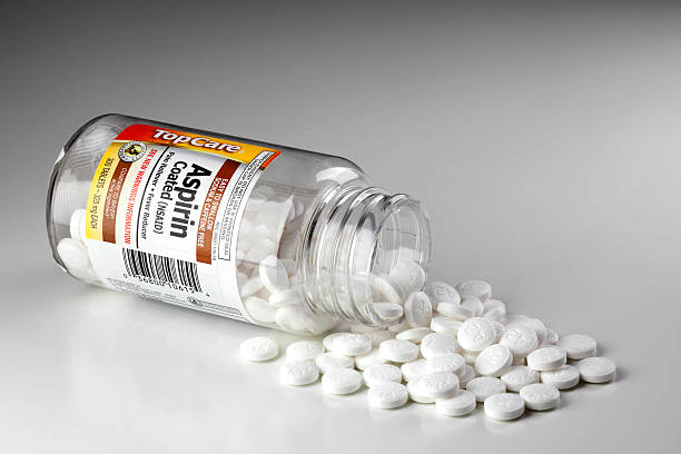 Aspirin bottle with tablets spilling out Chattanooga, United States - August 12, 2011: An opened bottle of aspirin lying on its side with tablets spilling out. Aspirin is commonly used for pain relief and fever reducer in adults. aspirin stock pictures, royalty-free photos & images