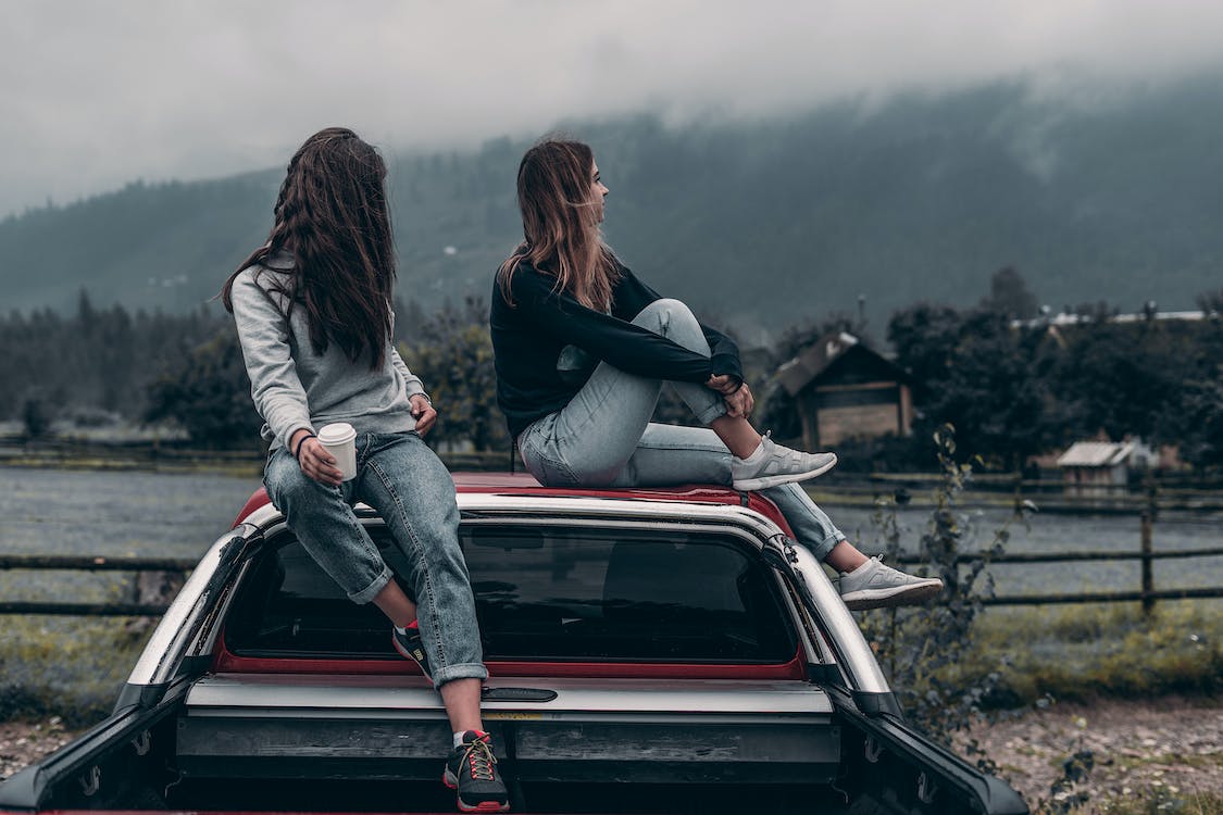 Free Two Women Sitting on Vehicle Roofs Stock Photo